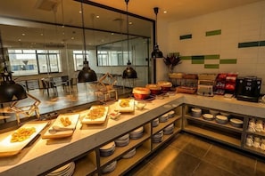 A modern kitchen with a long counter, various food items, and coffee machines. - Fragrans Hotel(Suzhou Lumu Metro Station Branch) (Suzhou)