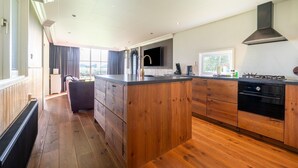 A modern kitchen with wooden cabinets, a central island, a stove, and a large window providing natural light.