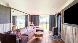 A spacious living room with a large sofa, a round coffee table, and a fireplace.