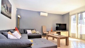 Una sala de estar moderna con un sofá modular, un televisor de pantalla plana, una mesa de centro y una lámpara de pie.