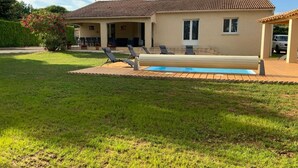 Una casa con piscina, patio cubierto y jardín.