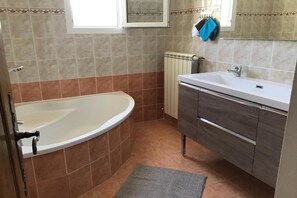 Un baño con bañera, lavamanos y espejo.