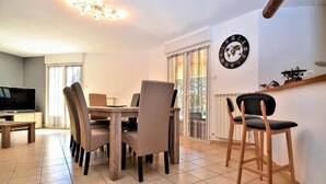 Un comedor con una mesa, sillas, un televisor y un reloj en la pared.