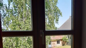 Une pièce dotée d’une grande fenêtre donnant sur une cour verdoyante et une maison.