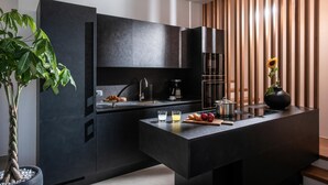 A modern kitchen with dark cabinetry, a built-in oven, and a central island with a sink. - Made By The Sea Villa 3 (Malevizi)