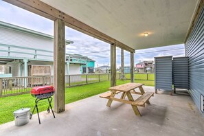 Un portico coperto con tavolo da picnic e barbecue.