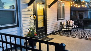 Une maison avec un porche, le numéro « 3460 » sur la porte, une plante en pot et un banc avec des coussins.