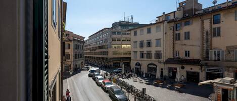 A street view with parked cars and bicycles, buildings with balconies, and a clear sky.