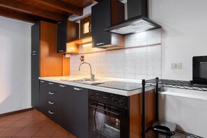 A modern kitchen with a built-in oven, a stainless steel sink, and wooden cabinets.