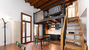 A compact kitchen with a dining area, a wooden staircase, and a view of the upper floor. - Appartamento Via Dell Oriuolo (Florence)