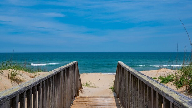 A wooden boardwalk leading to a beach with clear skies. - Barefootin'- Oceanfront, private pool, hot tub, pool table, private walkway to the beach! (Nags Head)