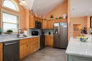Une cuisine moderne avec des meubles en bois, des appareils en acier inoxydable et un plan de travail en marbre.