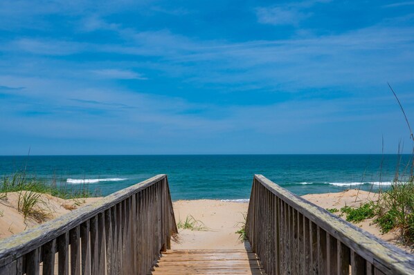 A wooden boardwalk leading to a beach with clear skies.