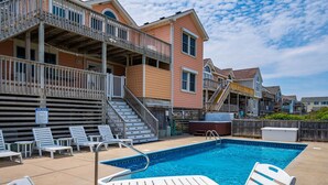 A swimming pool with lounge chairs and a wooden deck. - Barefootin'- Oceanfront, private pool, hot tub, pool table, private walkway to the beach! (Nags Head)