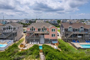 A beachfront property with multiple houses, each featuring a balcony and a pool.