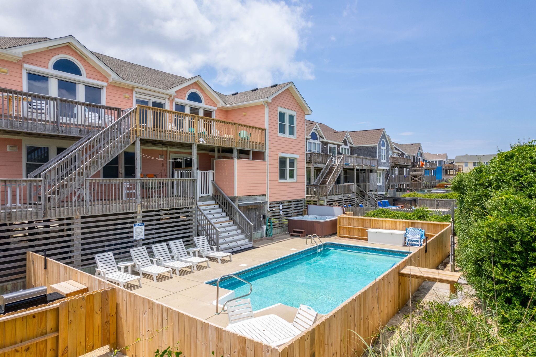 Área residencial com piscina, deck de madeira e várias casas de dois andares com varandas.
