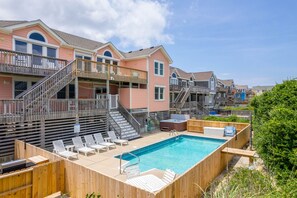 A residential area with a swimming pool, wooden deck, and multiple two-story houses with balconies.