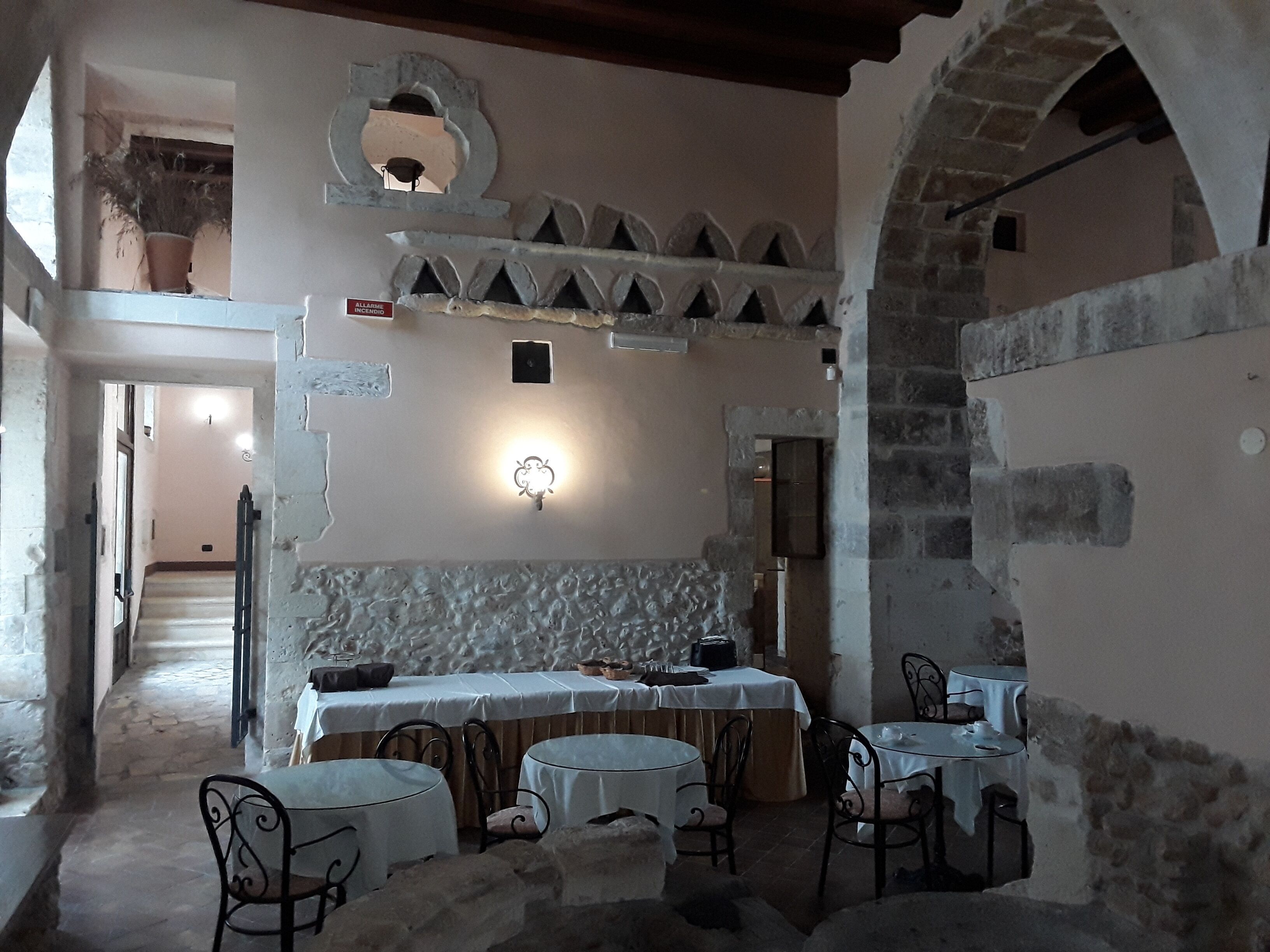 A rustic interior with stone walls, a stone fireplace, and a dining area with tables and chairs.
