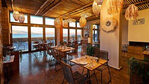 A restaurant with wooden ceiling and large windows overlooking the sea. Tables are set with plates and glasses. - Miramare Magnetic Beach Hotel (Kobuleti)