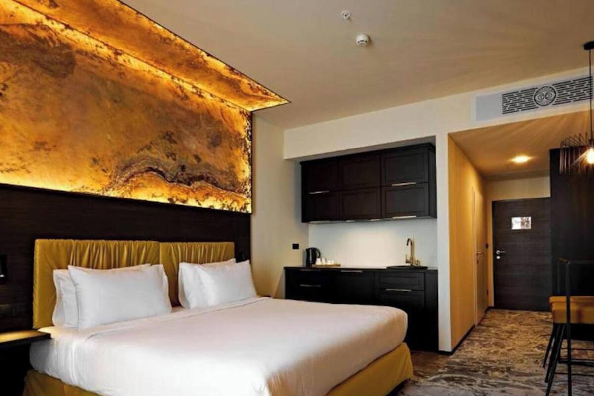 Ein Hotelzimmer mit einem großen Bett, einem Schreibtisch und einer Küchenzeile.