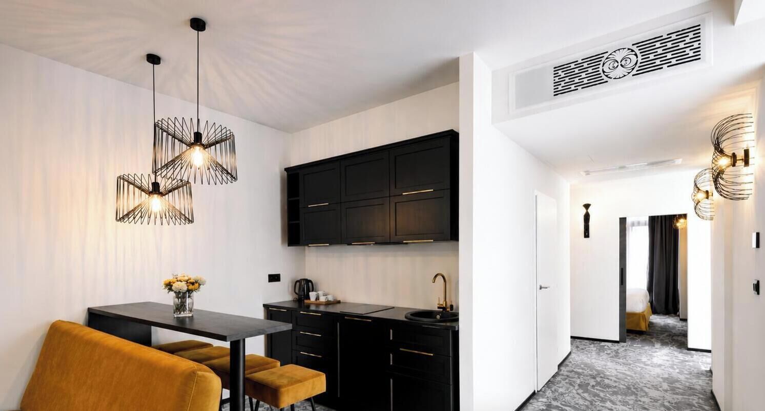 Una cucina moderna con mobili neri, un tavolo da pranzo con sedie e una lampada a sospensione.