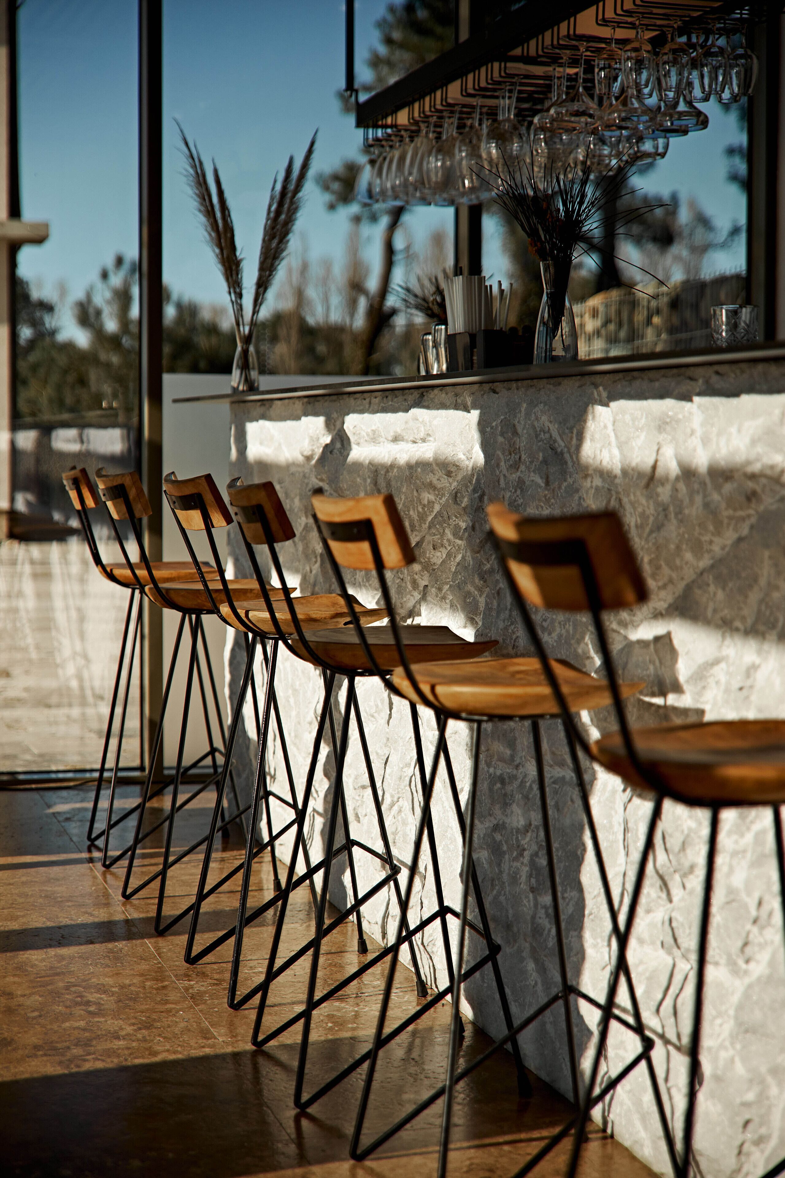 A bar area with wooden chairs and a stone wall.