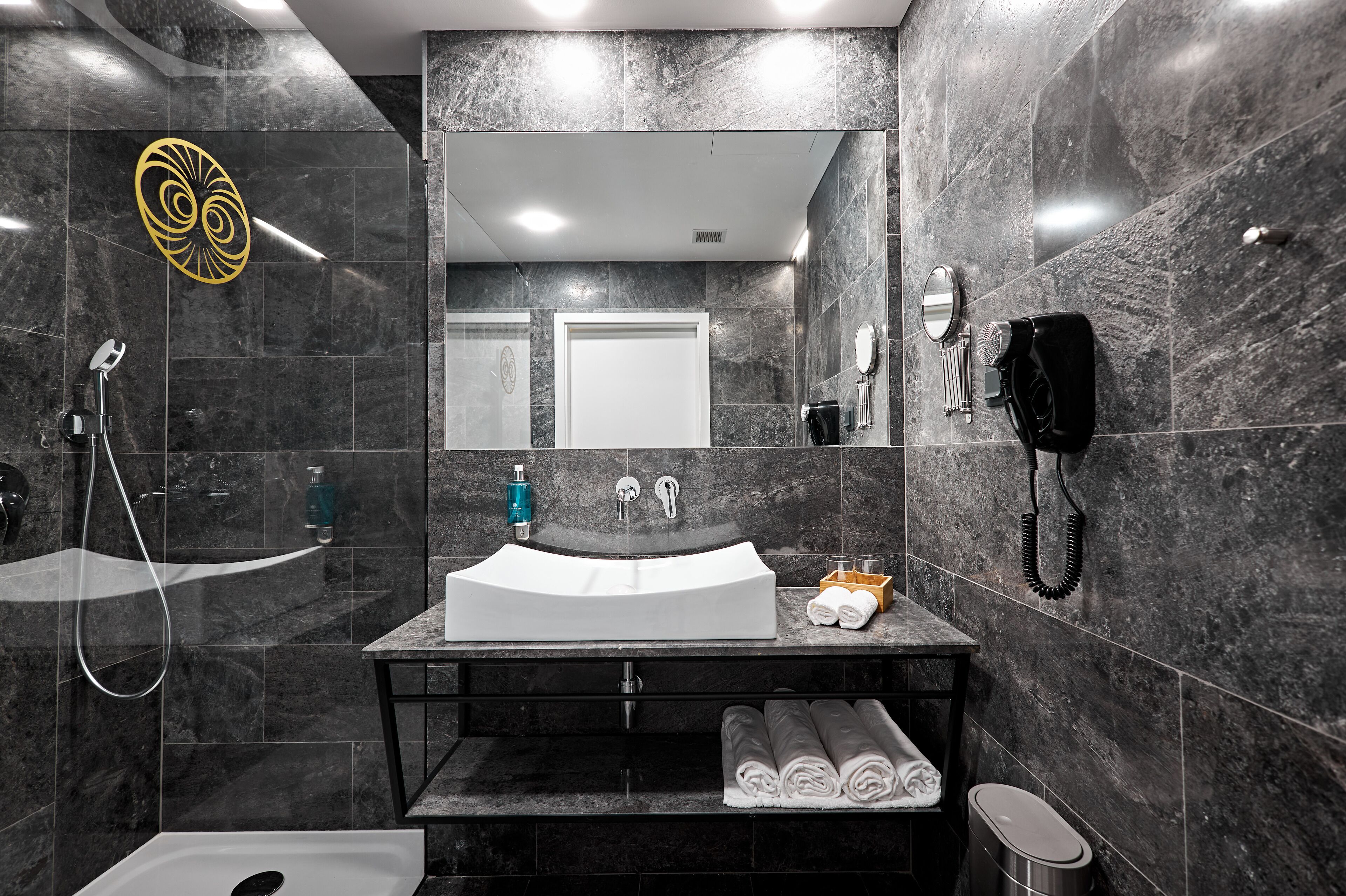 Un baño moderno con un lavamanos grande, un espejo, una ducha y un inodoro.