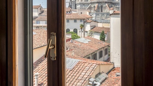 A view through a window of a building with a view of a historic dome and terracotta rooftops. - Appartamento Portinari (Florence)