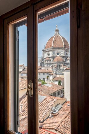 A view through a window of a building with a view of a historic dome and terracotta rooftops. - Appartamento Portinari (Florence)