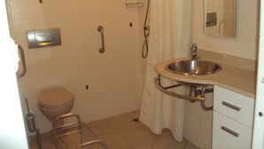 Un bagno con WC, doccia, lavandino e uno specchio.