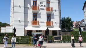 Un bâtiment portant l’enseigne « DE TORRE » et, en dessous, une autre enseigne indiquant « De Haan aan zee ».