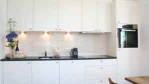 A kitchen with white cabinets, a black countertop, and a built-in oven. - De Torre 1 - luxury 1-bedroom apartment in iconic building (De Haan)
