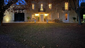 A stone building with a central entrance, two balconies, and a small patio area with outdoor seating. - Domaine de la Trinité (Mauguio)
