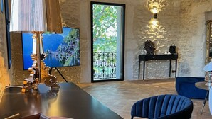 A dining area with a wooden table, chairs, and a lamp. There is a view of a balcony with a railing and a door. - Domaine de la Trinité (Mauguio)
