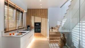 A modern kitchen with wooden cabinetry, a built-in oven, and a coffee maker.