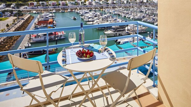 A balcony with a table set for two, overlooking a marina with boats. - Modern luxury apartment on the Albufeira Marina (Albufeira)