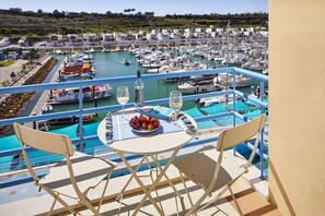 Un balcón con una mesa para dos, con vista a un puerto deportivo y barcos.