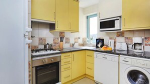 A compact kitchen with yellow cabinets, a Bosch microwave, a Bosch dishwasher, and a stove. - Modern luxury apartment on the Albufeira Marina (Albufeira)