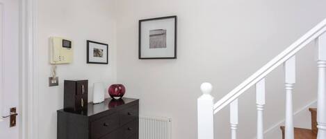 A hallway with a black dresser, a framed picture, and a white radiator.