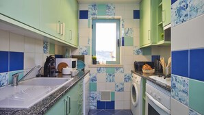 Une cuisine de taille réduite, dotée d’une fenêtre, d’un lave-linge et d’un four à micro-ondes.