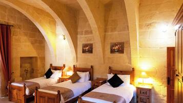 A room with four wooden beds, stone walls, and a wooden door.