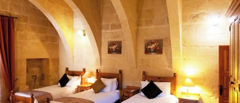 A room with four wooden beds, stone walls, and a wooden door.