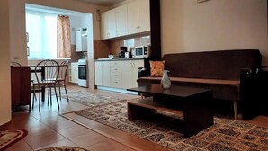 Een moderne woonkamer met een bank, salontafel en eethoek.