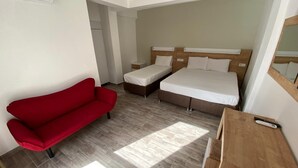 A hotel room with a red sofa, a bed, a wooden desk, and a mirror. - Bella Rose Hotel (Fethiye)