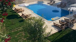 A hotel with a swimming pool surrounded by lounge chairs and umbrellas, set against a backdrop of mountains. - Bella Rose Hotel (Fethiye)