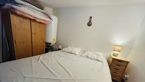 Ein Schlafzimmer mit einem Bett, einem Holzschrank, einem Nachttisch mit Lampe und einer Wanddekoration.