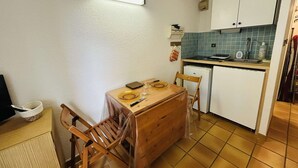 Eine kleine Küche mit Esstisch, Stühlen, einem Kühlschrank und einer Spüle.
