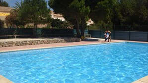 Ein rechteckiger Pool mit klarem, blauem Wasser, umgeben von einer Steinsäule und einer gefliesten Liegefläche.