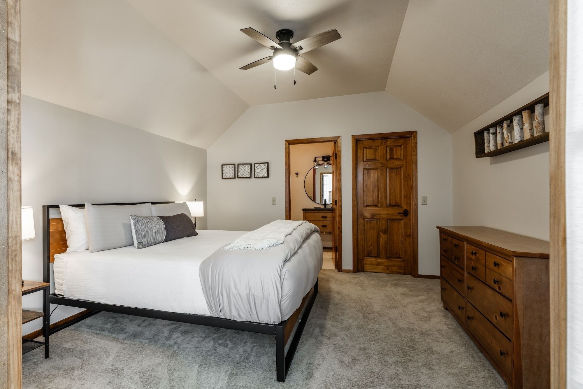 Un dormitorio con cama, cómoda, ventilador de techo y espejo.