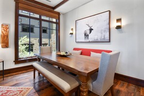 A dining area with a wooden table, benches, and a red cushioned bench.